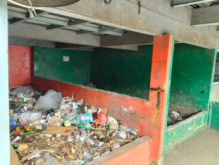 The photo shows a temporary waste disposal site  in an open area with red and green painted walls.