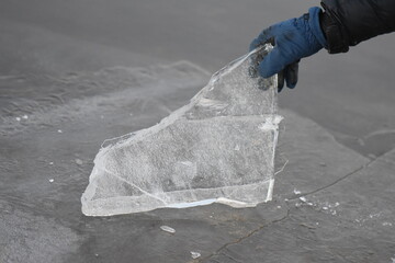 A man holding transparent piece of ice, sunset sky background