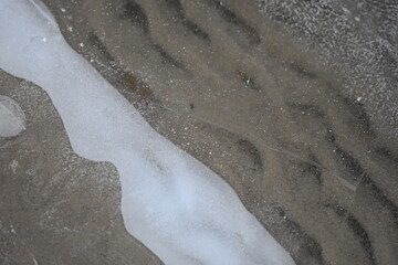 ice and snow on sandy beach in winter, closeup of photo