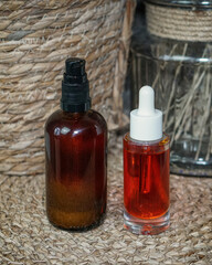 Amber glass bottle and transparent dropper bottle with homemade natural beta-carotene body oil on beige background. Clean beauty, DIY skincare, and eco-friendly cosmetic concept.