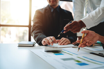 Young colleagues discuss business and analytical price charts using calculators and laptops to calculate financial, tax, accounting, statistics and analytical research ideas.