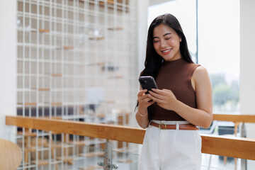 Young asian businesswoman using mobile phone in modern office building