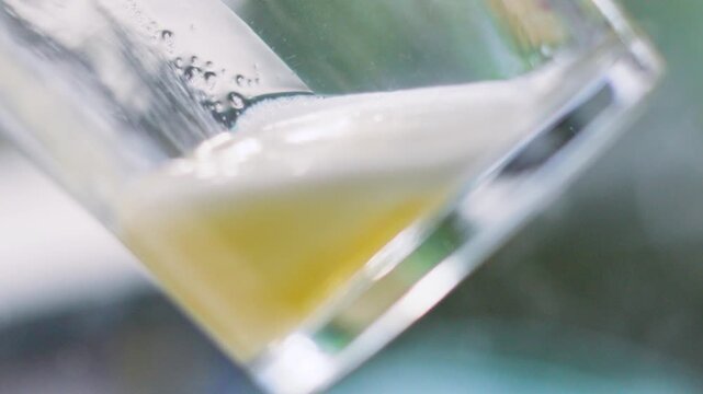 Lager Beer Slowly Pouring into Clear Pint Glass with Vibrant Froth and Color. Alcoholic Drink Enjoyed Outside in Summer.
