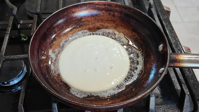 Homemade pancake batter getting cooked on steel pan with butter