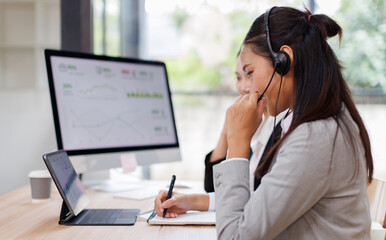 Asian Woman Wearing Headset Sitting At Desk Working In Office Call Centre Team
