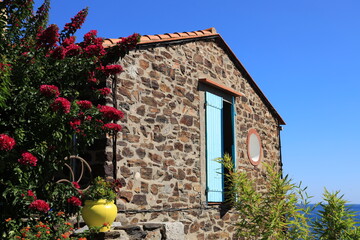 View of exterior of old house adorned with flowers in bloom, located in Mediterranean seaside town...