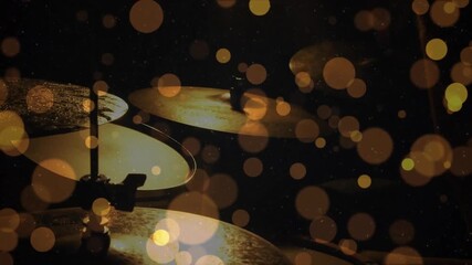 Stick tapping lower cymbal amid golden bokeh, drummer generating shimmer to highlight metallic glow
