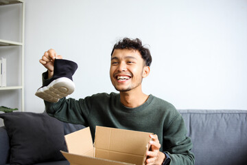 Excited Young Asian Man Unboxing New Pair Of Shoes Showing Them To The Camera