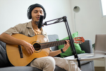 Young Asian Man Musician Singing Passionately Into Microphone While Playing Acoustic Guitar