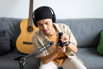 Young Asian Man In Headphones Adjusting Microphone Preparing For Online Recording Session