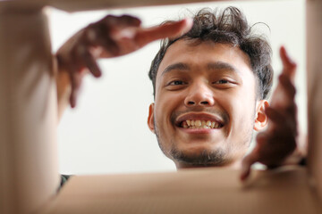 Happy Male Customer Looking Down Into Package Reaching For Contents During Unboxing