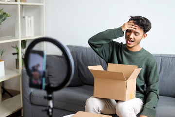 Happy Male Influencer Holding up a pair of new sneakers for his online video review