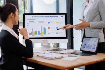 Asian business documents on office table with laptop computer and graph financial with social network diagram and three colleagues discussing data in the background

