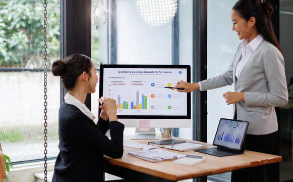 Asian business documents on office table with laptop computer and graph financial with social network diagram and three colleagues discussing data in the background
