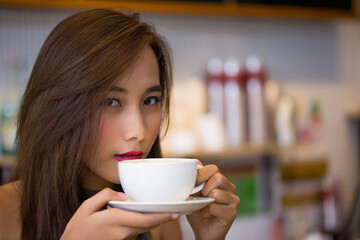 Close-up of serene Asian woman enjoying warm drink, capturing mindfulness and sensory appreciation...