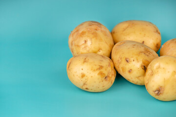 Whole fresh potatoes with natural skin placed on a bright turquoise background. Ideal for food and...