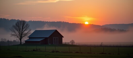 Barndominium concept. Serene sunrise over a farmhouse surrounded by misty fields and trees.