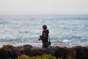 Side view of a woman walking on the rocks near the shore after the rain, looking at the ocean, Griffiths Island, Port Fairy, Victoria, Australia