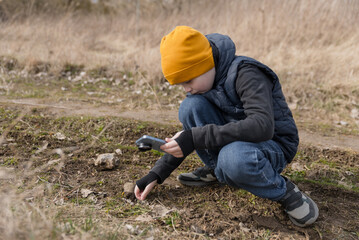 A little boy is photographing something on the ground. Childhood and gadgets.
