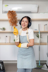 Home Cleaning. Smiling woman holding a duster while cleaning her home.