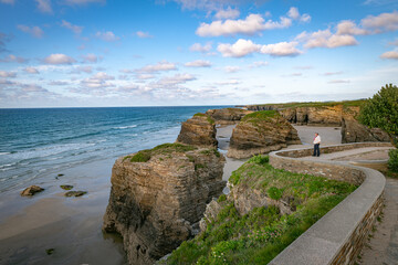 woman looking at the beautifull rocks at playa de cathedrales in spain