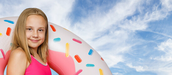 Close-up portrait of little girl and colorful inflatable ring swimming float against blue sky with...