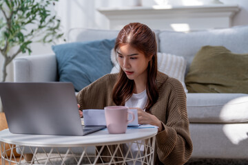 woman working on laptop at home, enjoying cup of coffee, surrounded by cozy decor. atmosphere is...