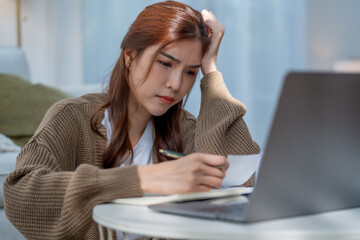 Struggling woman working on laptop, feeling stressed and overwhelmed while taking notes