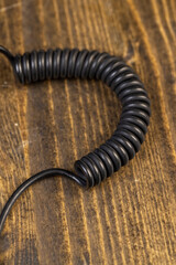 a cable twisted in the shape of a spring for equipment , an old black cable in a rubber braid for connecting different devices