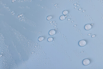 a smooth surface of light blue color covered with water droplets, a beautiful wet blue film in a large number of water droplets