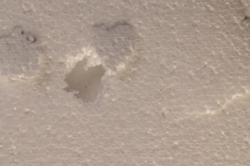 white foam for building insulation closeup, dents and damages in the foam, white foam made from a large number of spherical pieces joined together