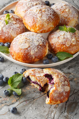 Traditional brioche buns with blueberry filling closeup on the plate on the table. Vertical