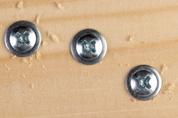 self-tapping screws with a drill tip twisted into a pine board, close up