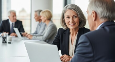 Mature businesswoman gray hair suit smiling meeting office laptop teamwork professional