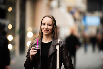Young woman smiling with juice in city center