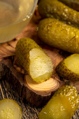 pickled marinated and pickled cucumbers next to a glass, poured pickle with spices and whole crispy cucumbers on a board