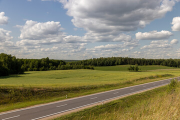 part of the paved road during the day in sunny weather , paved road for vehicles with white road markings