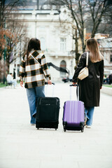 Young women with suitcases traveling and talking outside
