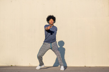 Young man in headphones pointing playfully while dancing in urban setting