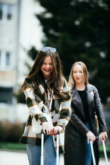 Young women with suitcases traveling and talking outside