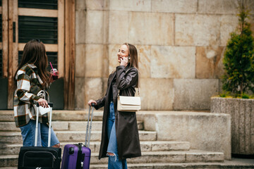 Young women with suitcases traveling and talking outside