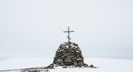 Fototapeta premium Snowy stone cairn with wooden cross in winter landscape
