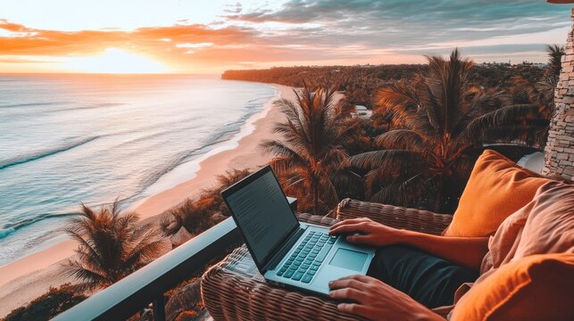 Laptop on balcony overlooking beach at sunrise