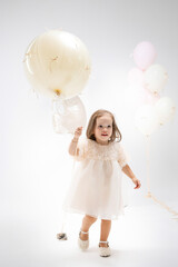 Little girl in white dress holding balloon during joyful celebration in bright studio