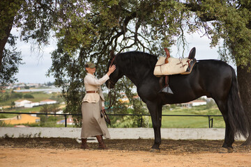 Young woman rider caressing her black Spanish thoroughbred horse, with affection and tenderness...