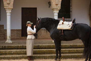 Young woman rider caressing her black Spanish thoroughbred horse, with affection and tenderness...