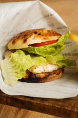 Chicken sandwich with fries on wooden board