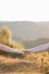 Couple holding hands during sunset in a serene outdoor landscape