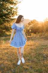 Young woman enjoying sunset in a floral dress on a grassy hillside