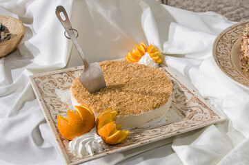 Whole, round cheesecake on a square platter and garnished with cut oranges and whipped cream.